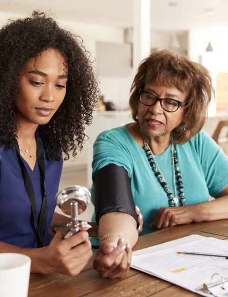 Female healthcare worker checking the blood pressure of a senior woman during a home visit